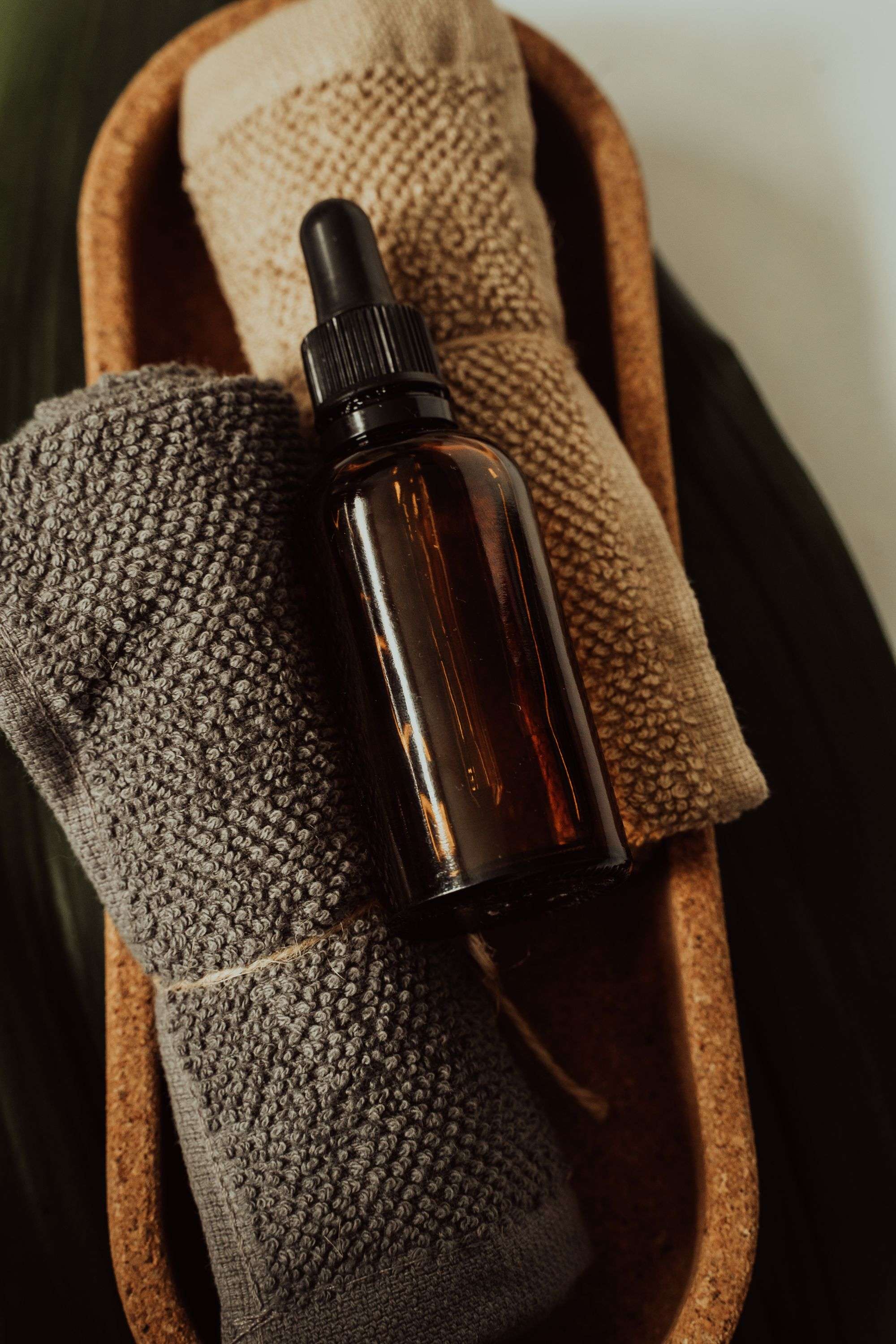 A compact amber bottle and folded towels on a tray