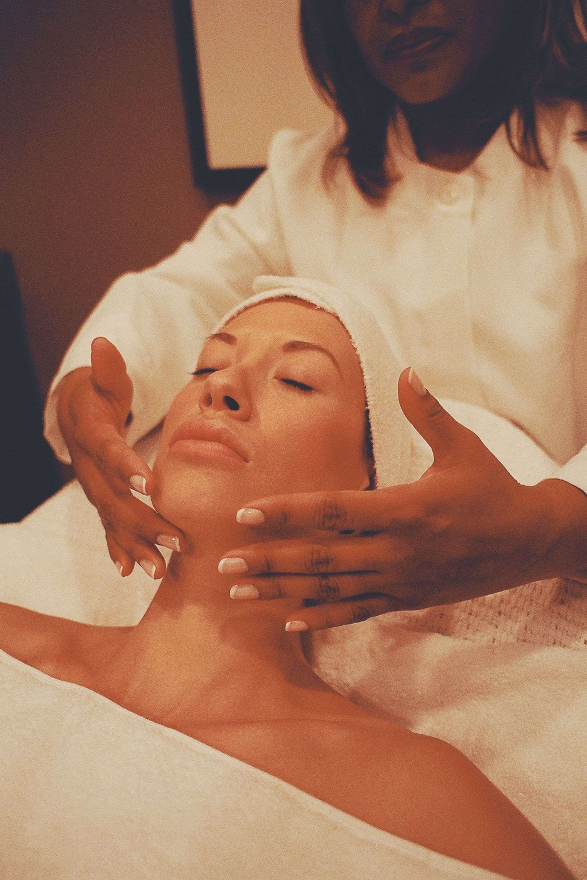 A guest's skin catching warm light during a facial treatment