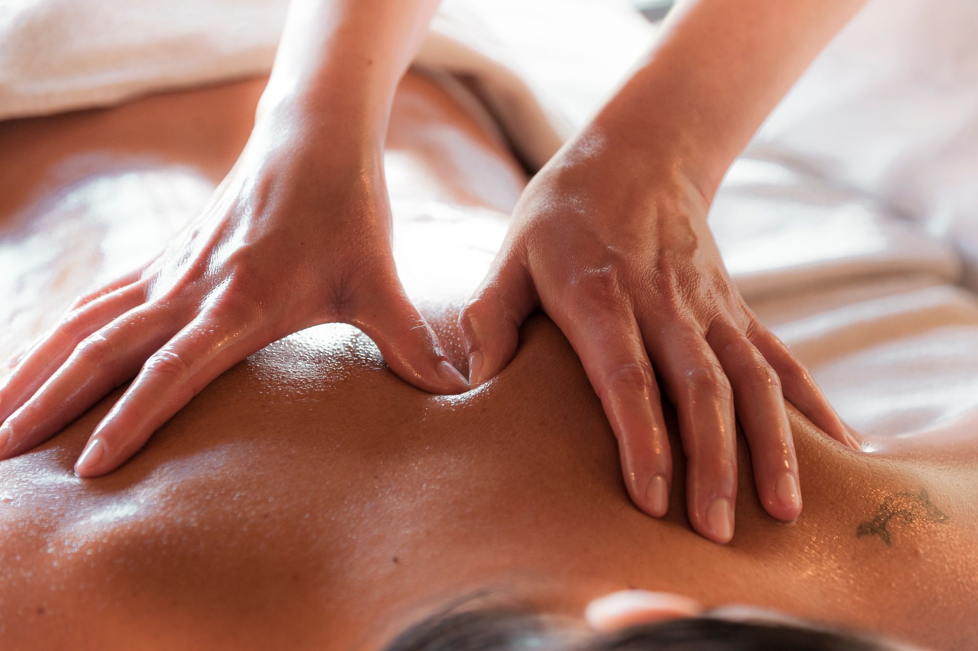Warm massage oil applied across a guest's back