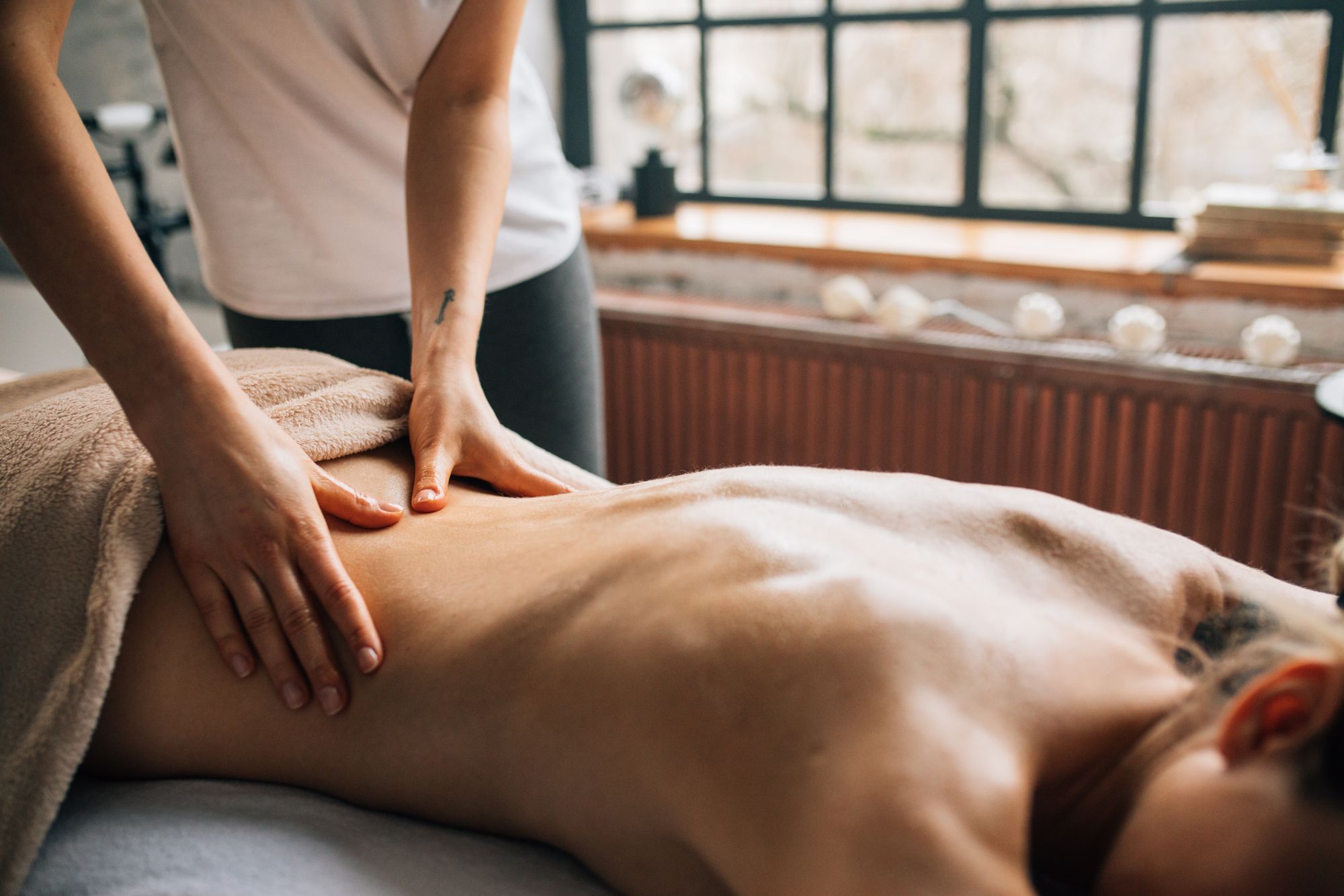 A woman receiving a warm oil massage in a softly lit room