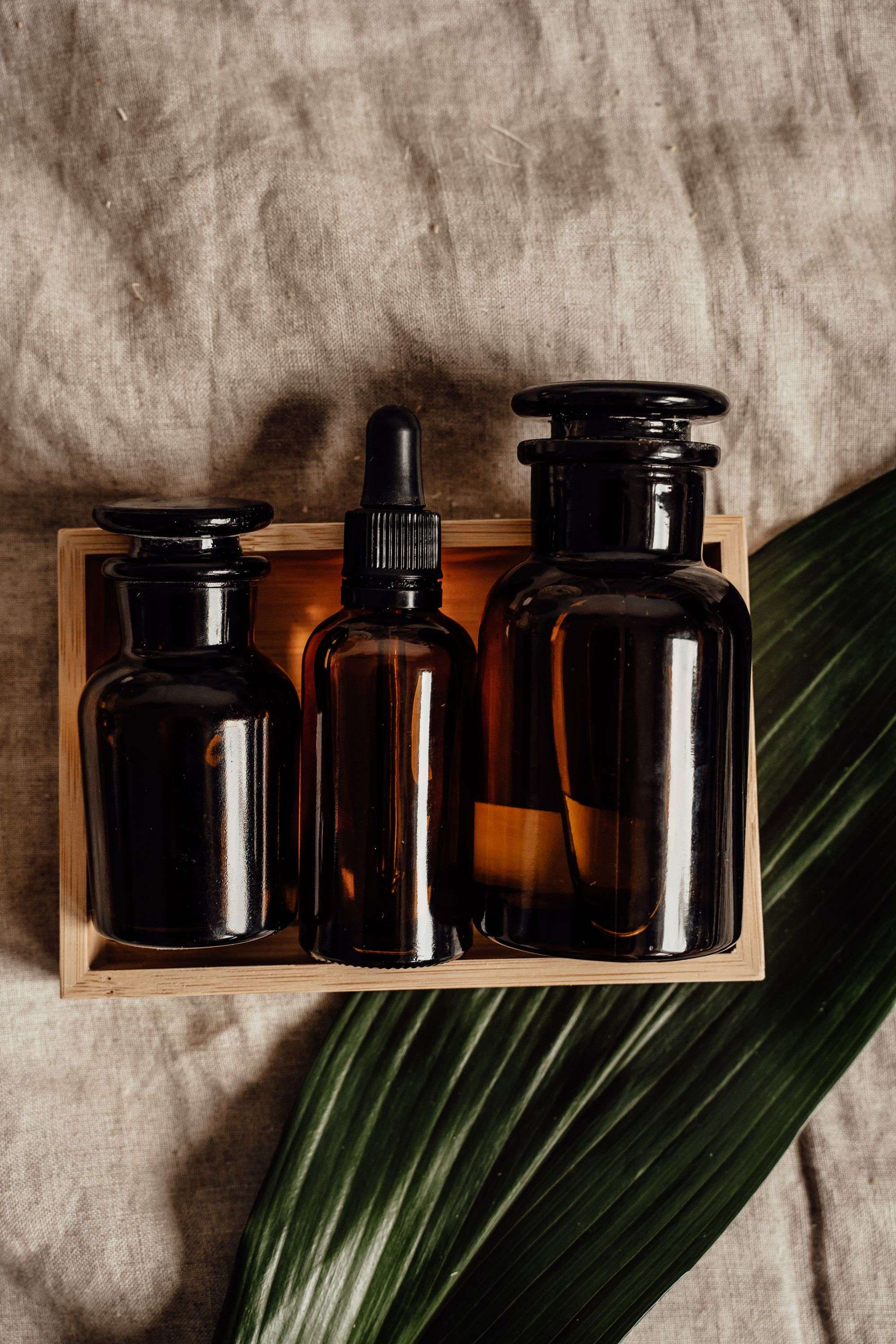 Amber skincare oil bottles resting on soft linen